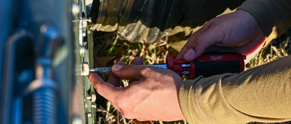 Hands with a screwdriver opening the panel of an outdoor AC unit