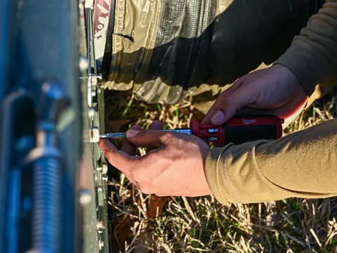 Hands with a screwdriver opening the panel of an outdoor AC unit