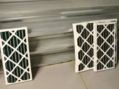 Pleated air filters leaning against a wall