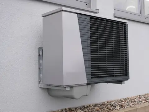 A heat pump outdoor unit mounted on a light wall