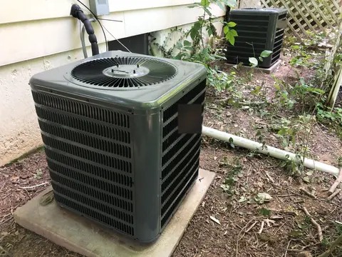 An outdoor AC unit on its pad beside a house