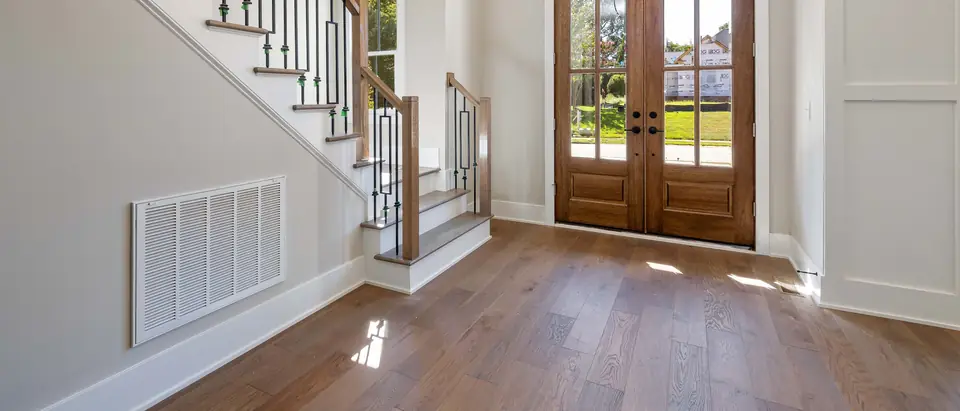 A bright entry hall with a large return air grille low on the wall