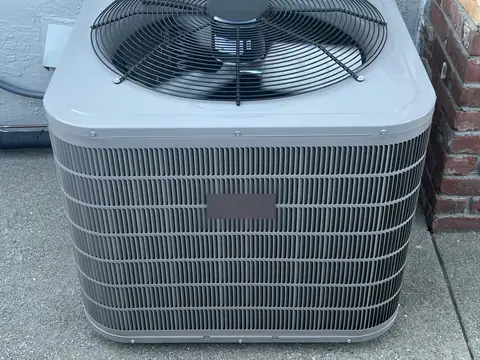 A new outdoor AC condenser set on its concrete pad