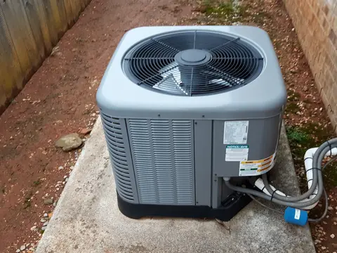 The fan and coil fins of an outdoor condenser on its pad