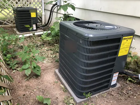 An outdoor condenser on its pad beside the house, its fan on top