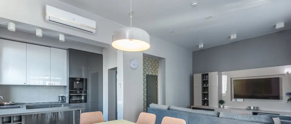 A bright kitchen and living room with a ductless air conditioner on the wall