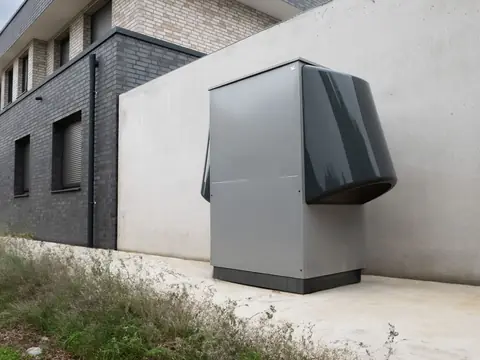 A new outdoor unit set on a pad beside a light wall