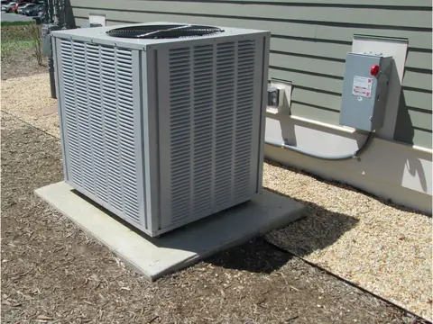 A new outdoor AC unit on a clean concrete pad beside a house